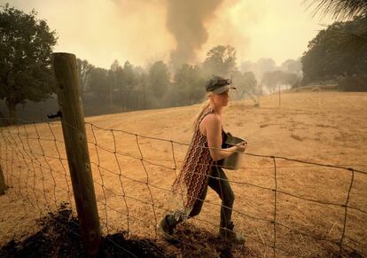 Moradora tenta apagar os incêndios ao redor de sua casa, em 6 de agosto de 2018 em Spring Valley, Califórnia.