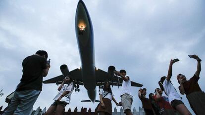 Un grupo de turistas se fotografía bajo un avión militar C-130 durante su aterrizaje en Taipéi (Taiwan).