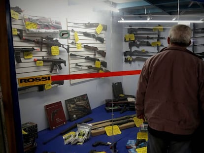 Homem observa vitrine com armas em São Paulo.