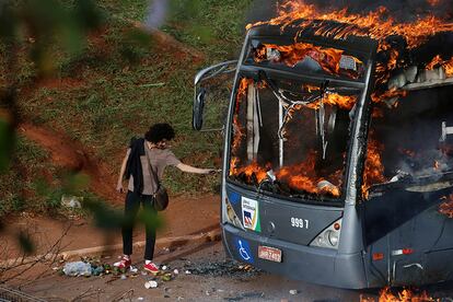 Un joven se enciende un cigarrillo con las llamas de un autobús que ha sido incendiado durante una protesta antigubernamental en Brasilia (Brasil), el 13 de diciembre de 2016.