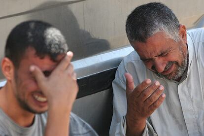 Dos iraquíes lloran, a las puertas del hospital, la muerte hoy de un familiar en un incidente armado en Bagdad.