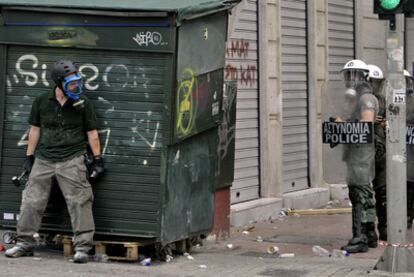 Un manifestante se esconde de la policía tras un kiosco, el pasado miércoles durante una protesta en el centro de Atenas.