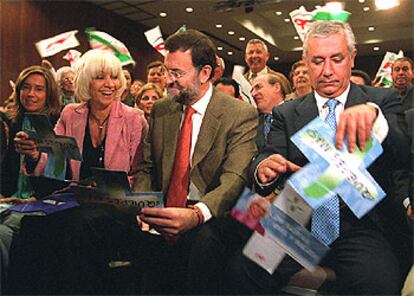 Teófila Martínez, Mariano Rajoy y Javier Arenas despliegan un folleto electoral.