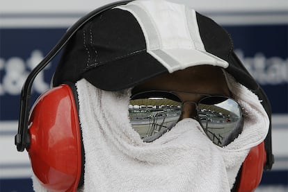 Un mecánico se protege del fuerte sol de Malaisia durante los entrenamientos de Sepang.