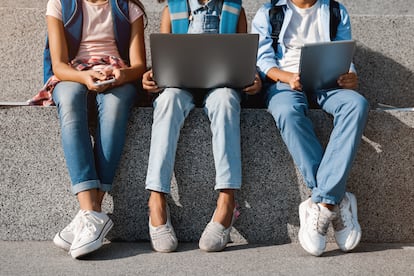 Tres jóvenes consultan dispositivos digitales en una imagen de archivo