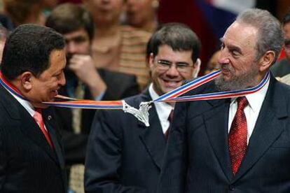 Fidel Castro (derecha) y Hugo Chávez bromean al engancharse las medallas que les impusieron estudiantes de la Escuela Latinoamericana de Medicina.