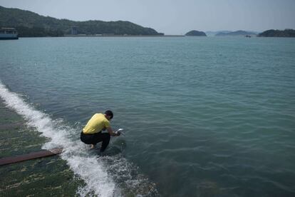 Un hombre lanza un mensaje al agua, en el lugar donde se hundió el ferry 'Sewol' en Jindo (Corea del Sur).