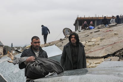 A man carries a victim as rescuers search for survivors under the rubble, following an earthquake, in rebel-held town of Jandaris, Syria.