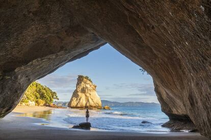 Una mujer frente al arco de piedra de Cathedral Cove, en Nueva Zelanda.