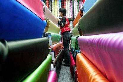 Una vendedora de telas aguarda en Pekín a que los clientes acudan a la tienda.