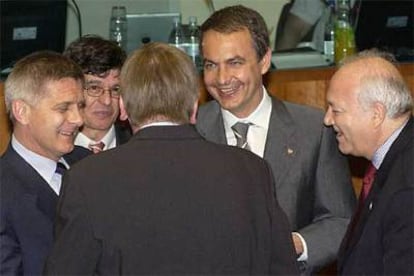 Zapatero (de frente) y  Moratinos (dcha.) charlan con el primer ministro belga (de espaldas), a su llegada a Bruselas.