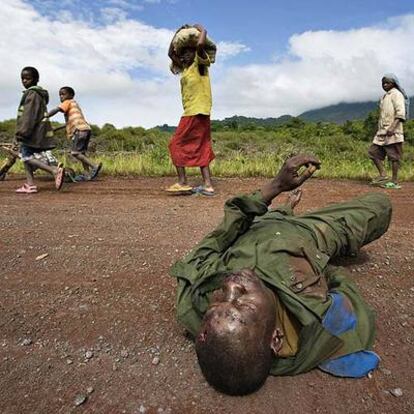 Un grupo de refugiados congoleños pasa delante de un soldado muerto en combate cerca de Goma.