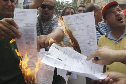Funcionarios griegos protestan con la quema de liquidaciones de un impuesto.