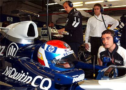 Xevi Pujolar, agachado, habla con Marc Gené, dentro del bólido, en el taller de Williams BMW.