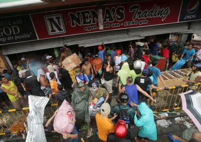 Filipinos de la ciudad de Tacloban asaltan una tienda de comestibles.