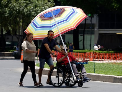 Una familia pasea protegida por una sombrilla en un parque en Ciudad de México.