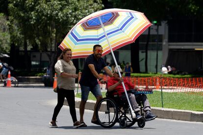 Una familia pasea protegida por una sombrilla en un parque en Ciudad de México.