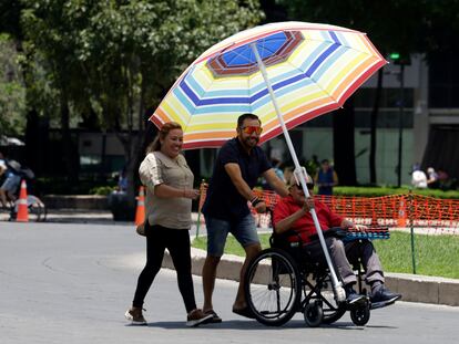 Una familia pasea protegida por una sombrilla en un parque en Ciudad de México.