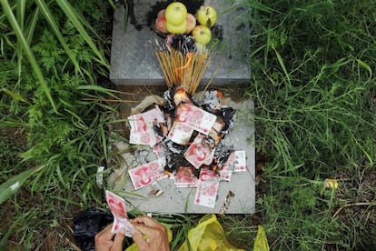 Zhang Shuangbing, investigador independiente sobre los abusos a las mujeres de solaz durante la guerra, quema unas barritas de incienso y dinero falso después de llevar a los reporteros a la tumba de Liu Mianhuan en las montañas.