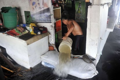 Un hombre achica agua de su casa en una zona inundada debido a un fuerte oleaje del océano en La Libertad, a 34 km al sur de San Salvador, el 3 de mayo de 2015. La actividad comercial y el turismo en la zona ha sido suspendida debido a la magnitud de las olas. Tres personas han muerto , uno está desaparecido y cientos tuvieron que evacuar después de fuertes olas azotaron la costa del Pacífico de los países de América Latina desde México hasta Chile .