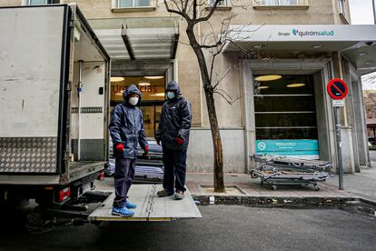 Dos trabajadores protegidos con mascarilla descargan las camas nuevas del camión que ha recibido la Clínica Ruber de Madrid para poder ayudar y dar servicio a más pacientes infectados con coronavirus en la capital, en Madrid, el 27 de marzo de 2020.
