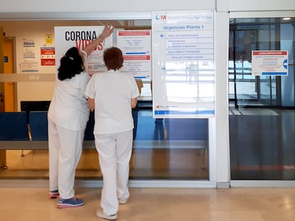 Dos enfermeras colocan un cartel con recomendaciones para el coronavirus en la sala de urgencias del Hospital Clínico San Carlos.