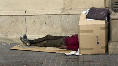 Un mendigo duerme en plena pla&ccedil;a de Catalunya,