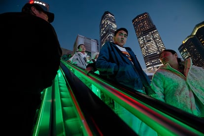 Varias personas viajan en una escalera mecánica en el distrito financiero de Lujiazui, en Shanghai, este jueves.