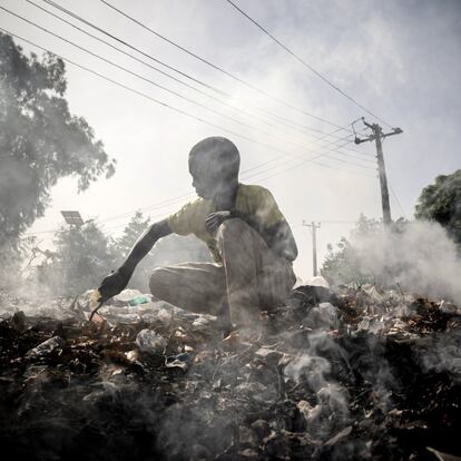 Muhammad Modu, de 15 años y desplazado interno de Malori, excava en el  vertedero de un recinto cerrado junto a la carretera principal que atraviesa  Maiduguri, Nigeria, para buscar artículos que puedan ser revendidos, el 24 de marzo de 2016. Muhammad tamiza a través de la humeante basura bajo un sol aplastante. Después de dos o tres días de este minucioso trabajo, Muhammad reúne material suficiente para vender por unos 75 centavos de dólar.