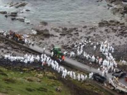 Miembros de las fuerzas armadas y voluntarios desplegados en la costa gallega entre Corcobión y Lira retiran el chapapote vertido por el Prestige y recogido en esta zona con contenedores y tractores EFE/Archivo