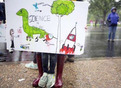 Una niña sujeta una gran pancarta en la que se aprecia la frase: 'La ciencia es real' acompañada con una serie de dibujos, en la explanada que va desde el Monumento a Washington hasta el Capitolio, en Washington DC.