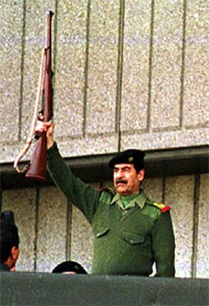 Sadam Husein dispara un fusil durante un desfile militar en Bagdad.