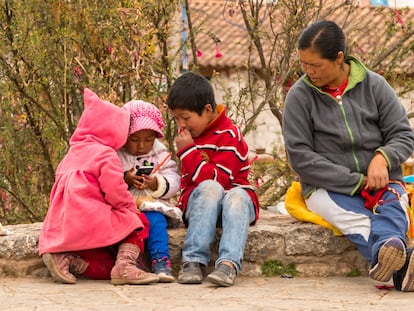 Una mujer indígena vigila a sus hijos que juegan con un teléfono móvil en Chinchero, Perú, en 2015.
