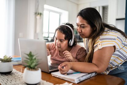Una madre ayuda a una niña con autismo a usar una computadora portátil en casa.