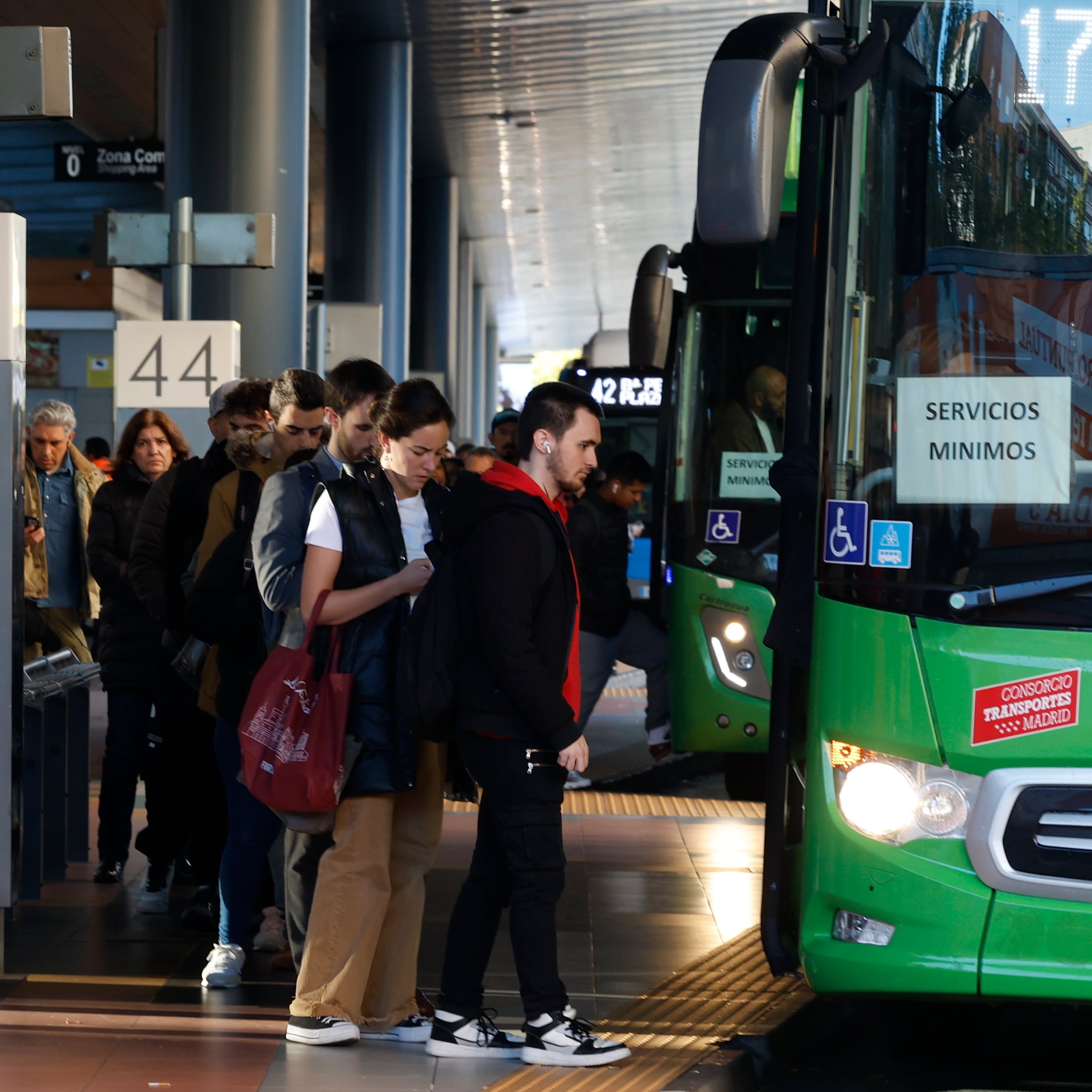 Varios usuarios del transporte público se suben a uno de los autobuses de los servicios mínimos en un intercambiador de autobuses en Madrid.