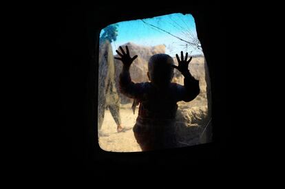 Un niño afgano desplazado internamente mira desde una ventana en su hogar temporal, en un campamento de refugiados a las afueras de Herat (Afganistán).