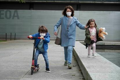 Una mujer pasea junto a una niña y un niño en patinete en Bilbao.
