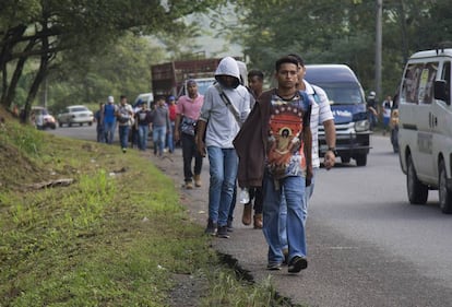 Miembros de la caravana migrante caminan a su salida de San Pedro Sula