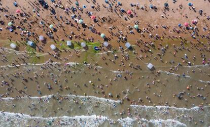 Bañistas se refrescan en una playa en Qingdao, provincia de Shandong (China). El presidente de Estados Unidos, Donald Trump, avanzó el jueves hacia el choque comercial total con el anuncio de nuevos aranceles para productos chinos por valor de 300.000 millones de dólares, a los que la potencia asiática respondió dejando caer su divisa con fuerza.