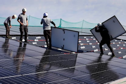 Varios operarios instalan paneles solares en el tejado de una planta industrial en Vic (Barcelona).