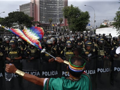 Un manifestante ondea una bandera wiphala de los pueblos indígenas frente a agentes de la Policía, este viernes durante la movilización convocada en Lima.
