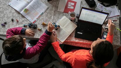 Una mujer teletrabajando junto a su hijo.