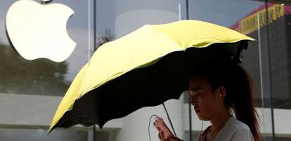 Una mujer utiliza un tel&eacute;fono m&oacute;vil en la puerta de una tienda de Apple en Pek&iacute;n. 