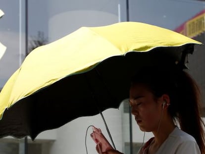 Una mujer utiliza un tel&eacute;fono m&oacute;vil en la puerta de una tienda de Apple en Pek&iacute;n. 