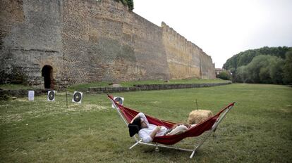 Un hombre con vestimenta medieval descansa frente a las murallas de Mansilla de las Mulas durante una celebración de feria medieval.