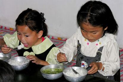 Dos niñas se alimentan de un bol de arroz y una sopa de hojas en una escuela estatal de Corea del Norte.