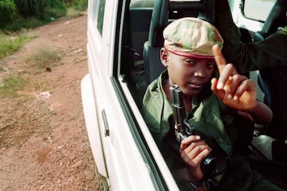 Un niño armado con una pistola patrulla las calle de Kigali en un automóvil junto a partidarios del Frente Patriótico de Ruanda, el 9 de junio de 1994.