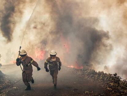 Dos bomberos se alejan de un incendio en Portugal el pasado junio.