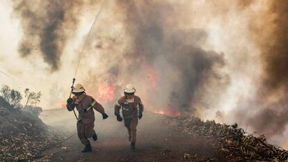 Dos bomberos se alejan de un incendio en Portugal el pasado junio.