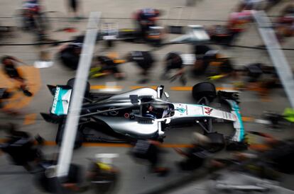 Miembros del equipo Mercedes se acercan al coche de Lewis Hamilton para realizar a cabo un cambio de neumáticos, durante el GP de Malasia, en el circuito de Sepang.